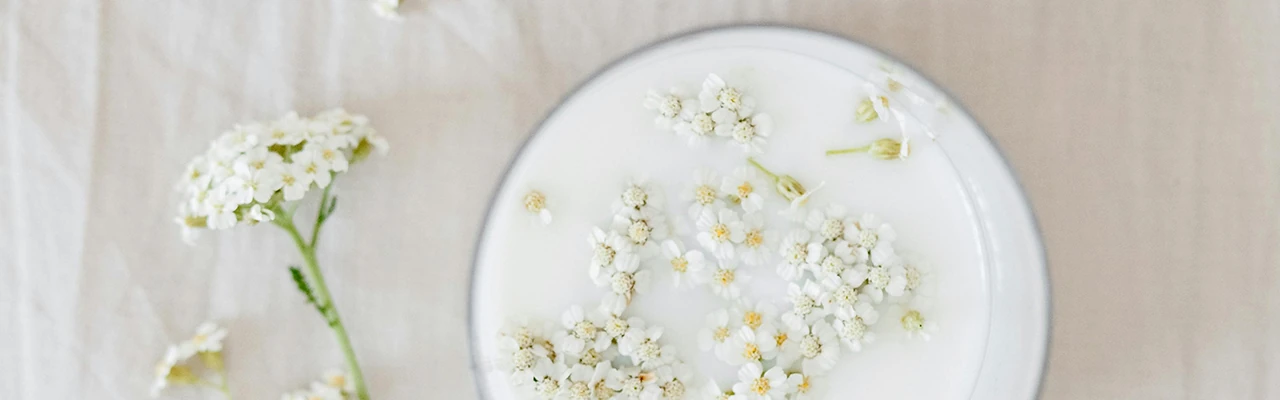top view glass with milk with floating yarrow flower