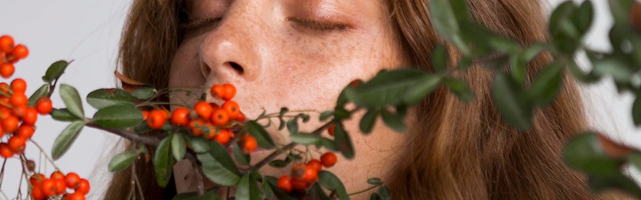 woman with closed eyes and orange berries plant